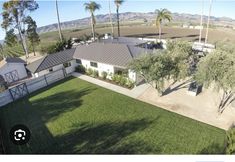 an aerial view of a house with palm trees and mountains in the background