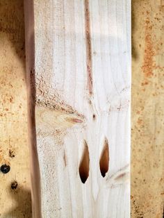 two holes in the side of a piece of wood that has been stained white with brown spots