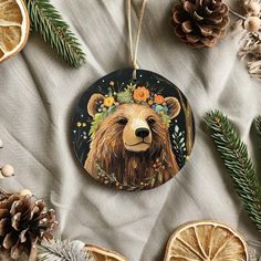 an ornament with a bear's head on it surrounded by pine cones and oranges