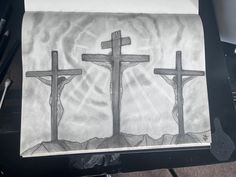 a drawing of three crosses on a piece of paper with crucifixs in the background