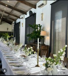 a long table is set with white flowers and place settings for an elegant dinner party