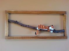 a wooden frame with a stuffed tiger on it's side hanging from a tree branch