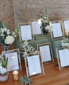 a table topped with lots of green boxes filled with flowers and place cards on top of each other