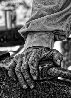 an old person's hand on top of a wooden rail with graffiti written on it