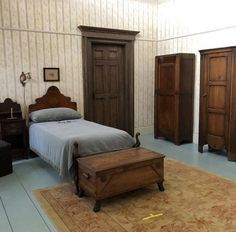 a bed room with a neatly made bed and wooden dressers on the wall next to it