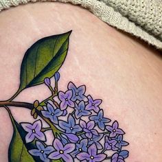 a woman's stomach with a tattoo of purple flowers and leaves on the side