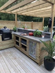 an outdoor kitchen with grill, sink and potted plants on the counter top area