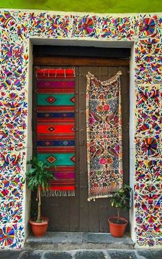 a door with a rug hanging on the side and potted plants next to it