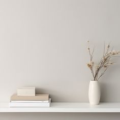 a white vase sitting on top of a book shelf next to a stack of books