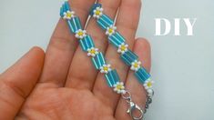 a hand holding a beaded bracelet with flowers and beads on the end of it