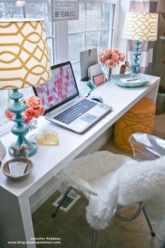 a laptop computer sitting on top of a white desk next to a lamp and chair