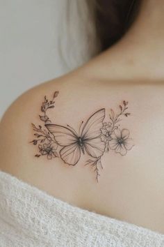 a woman's shoulder with a butterfly and flowers tattoo on her left shoulder,