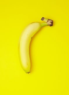 a banana on a yellow background with the peel still attached to it's end