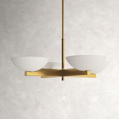 a modern light fixture with two white glass bowls hanging from it's brass frame