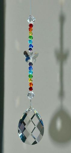 a multicolored bead hanging from a hook with a cross in the background