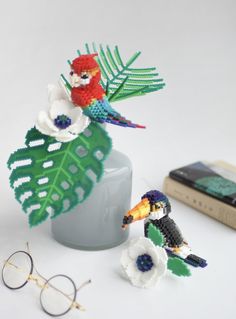 two small birds sitting on top of a plant next to a pair of eyeglasses