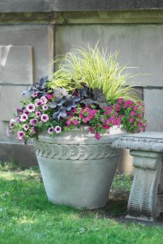 a cement bench sitting next to a flower pot filled with flowers