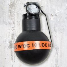 a black bomb with an orange stripe around the top and words on it that read, dewoc 101 / och