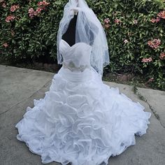 a wedding dress on display in front of some bushes