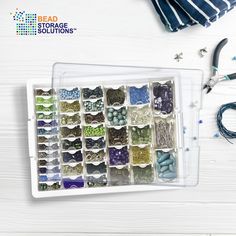 an assortment of bead supplies and scissors on a white wooden background with the bead storage solution logo