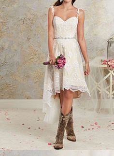 a woman in a short white dress and cowboy boots is posing for the camera with her bouquet