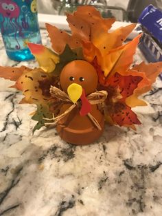 a turkey made out of leaves sitting on top of a marble counter next to a water bottle