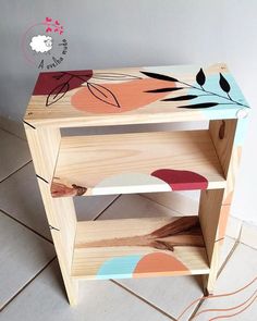 a wooden shelf with an animal design painted on the top and bottom, sitting on a tile floor