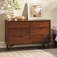 a wooden dresser sitting next to a bed in a room with a potted plant on top of it