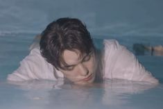 a young man is floating in the water with his head above the water's surface