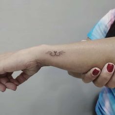 a woman's arm with a small cat tattoo on the left side of her wrist