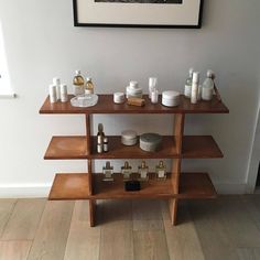 a wooden shelf with bottles and containers on it next to a framed photograph hanging on the wall