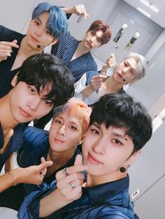 group of young men standing in front of a mirror making the peace sign with their fingers