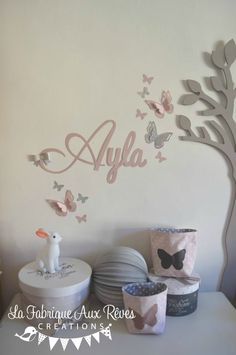 a white wall with butterflies on it and the name alila written in large letters