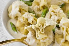 a bowl filled with pasta and asparagus on top of a white table cloth