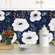 a kitchen counter with flowers on the wall behind it and plates, utensils and cups