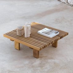 a wooden table sitting on top of a cement floor next to a book and cup