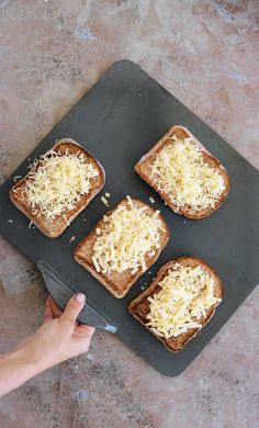 four pieces of toast with cheese on them being held by a person's hand