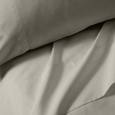 an unmade bed with white sheets and pillowcases on top of each other