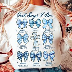 a woman wearing a white shirt with blue bows on it and the words god says i am