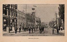 an old black and white photo of people walking down the street