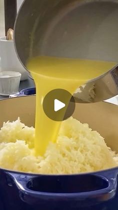 a person pouring yellow liquid into a pot filled with rice