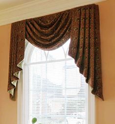 a living room with a large window covered in drapes and curtains on the windowsill