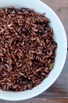 a white bowl filled with brown rice on top of a wooden table