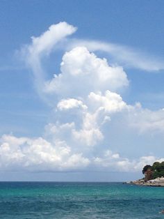 an airplane flying over the ocean on a clear day with blue sky and clouds in the background