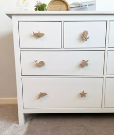 a white dresser with several drawers and some decorations on top of it in a room