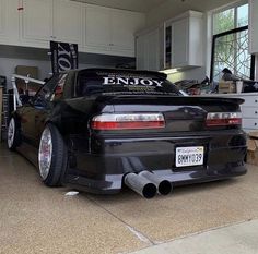 the back end of a black sports car parked in a garage