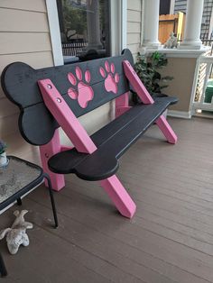 a pink and black bench with paw prints on the backrest, sitting on a porch