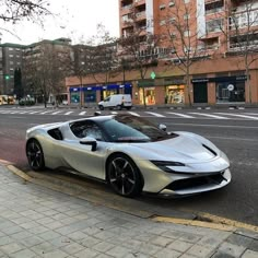 a silver sports car is parked on the side of the road in front of some buildings