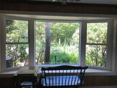 a room with two large windows and a rocking chair in front of the bay window