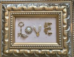 there is a gold frame with some jewelry in it and the word love spelled out